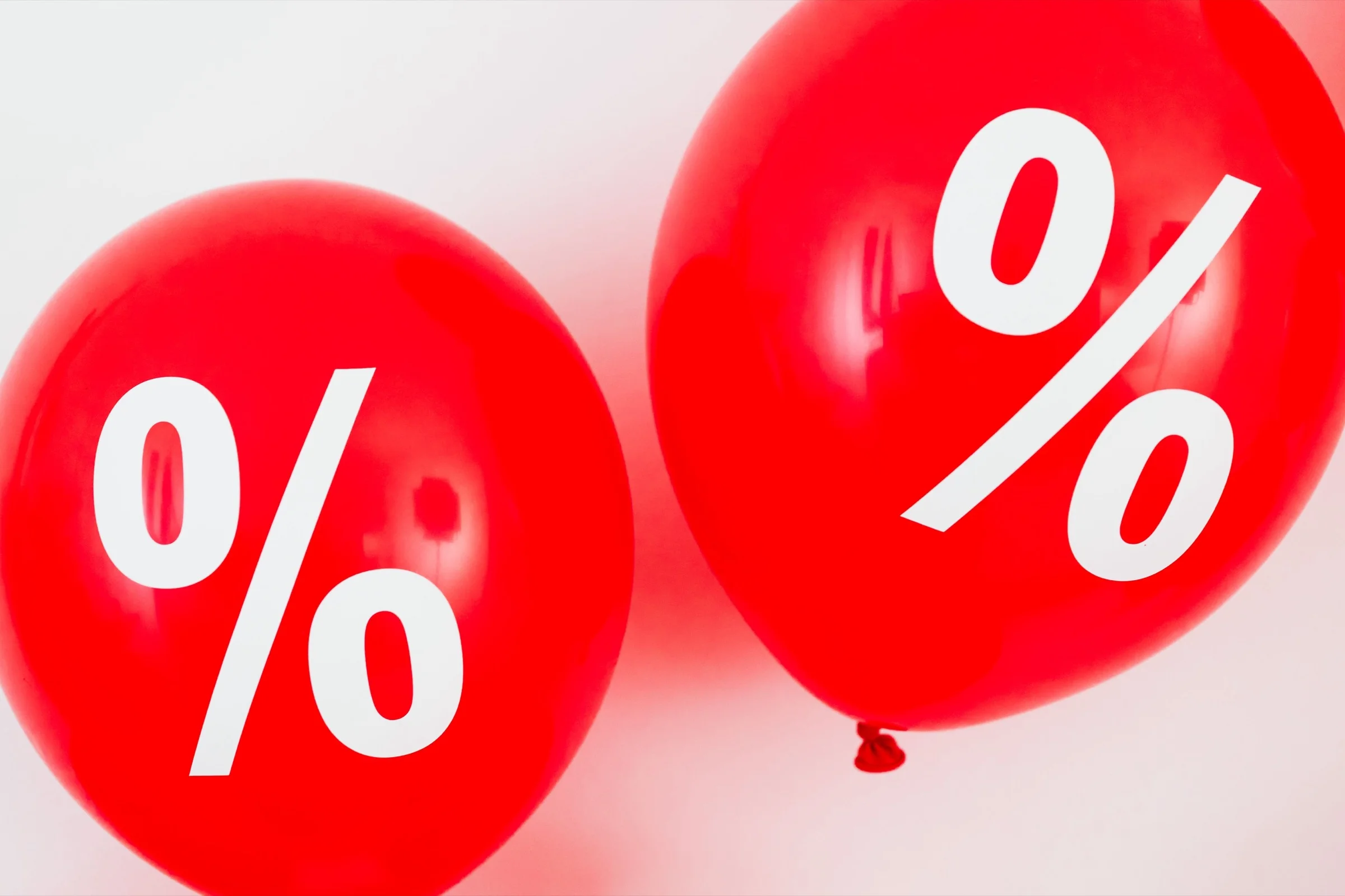 Two red balloons printed with percentage signs