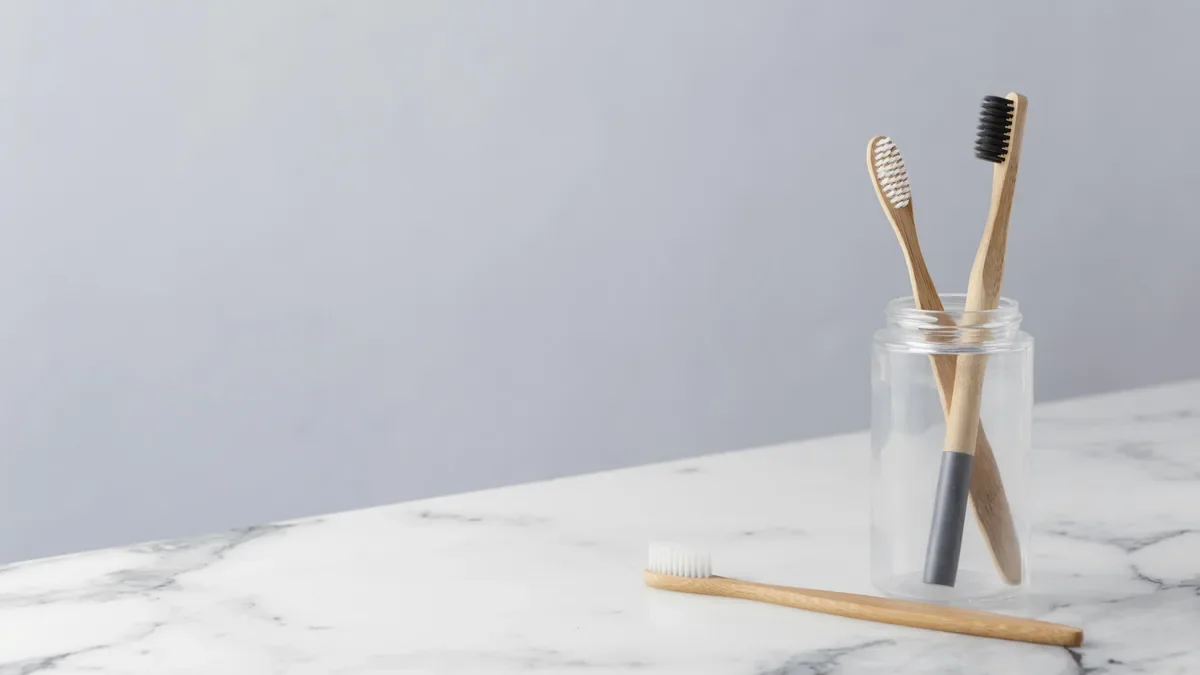 Bamboo toothbrushes in a glass jar with another toothbrush lying on a marble benchtop