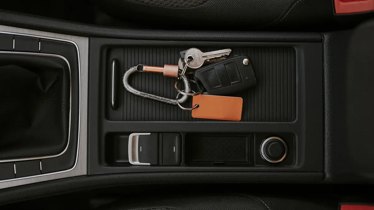 Car keys with a leather tag resting in the centre console tray of a vehicle