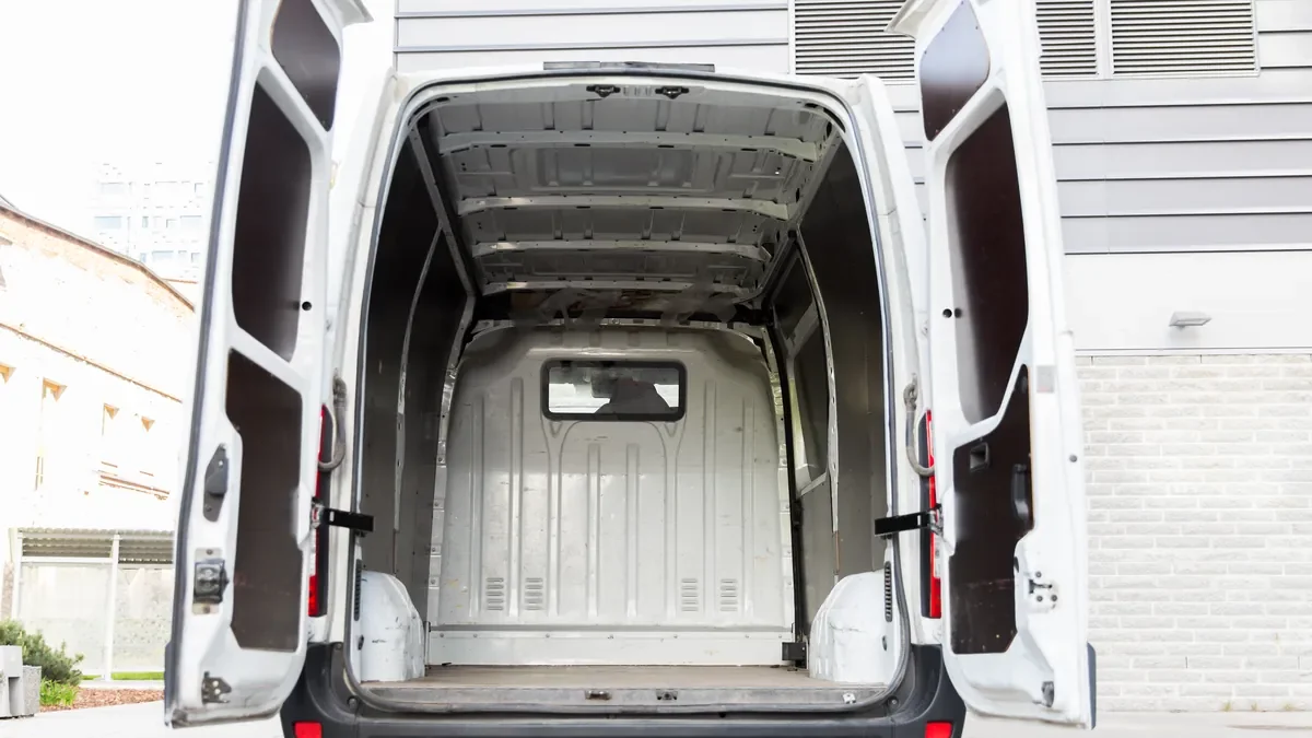 Empty white delivery van parked with both rear doors open, showing the bare cargo area