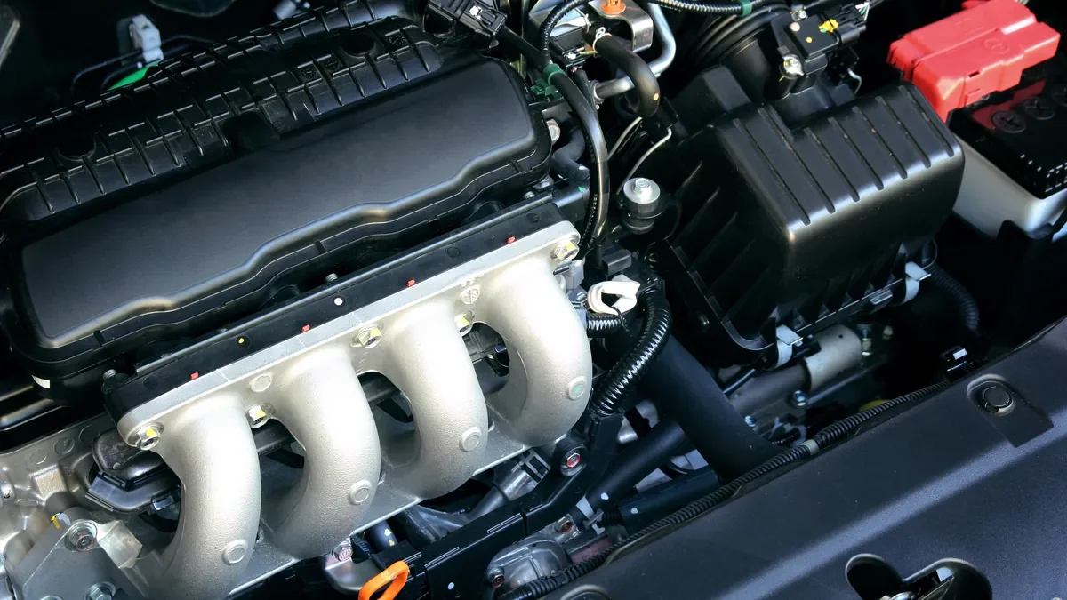 Engine bay of a small car with the bonnet open, showing the intake manifold and battery