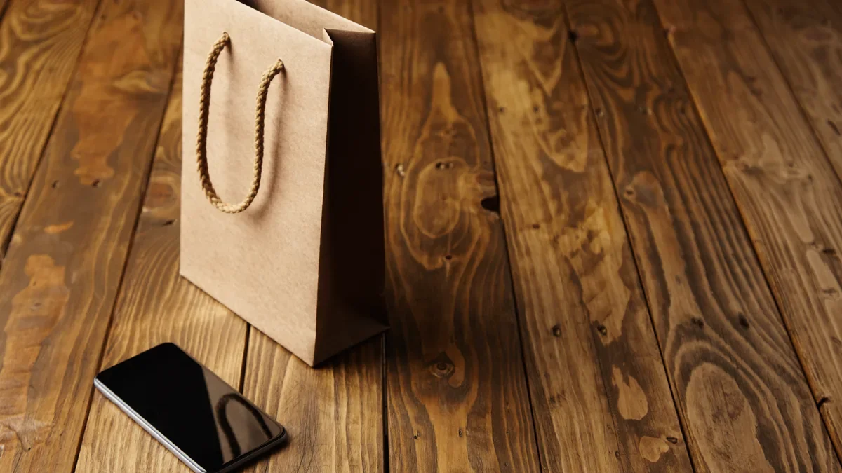 A brown paper shopping bag and a black smartphone with a blank screen on a wooden table