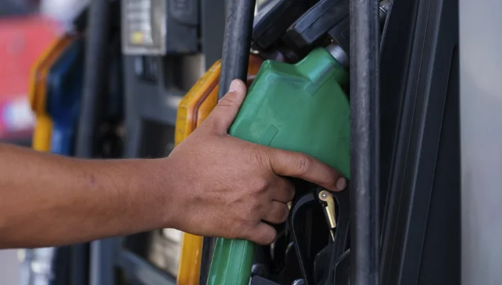 Driver taking a green fuel nozzle from the pump at a service station