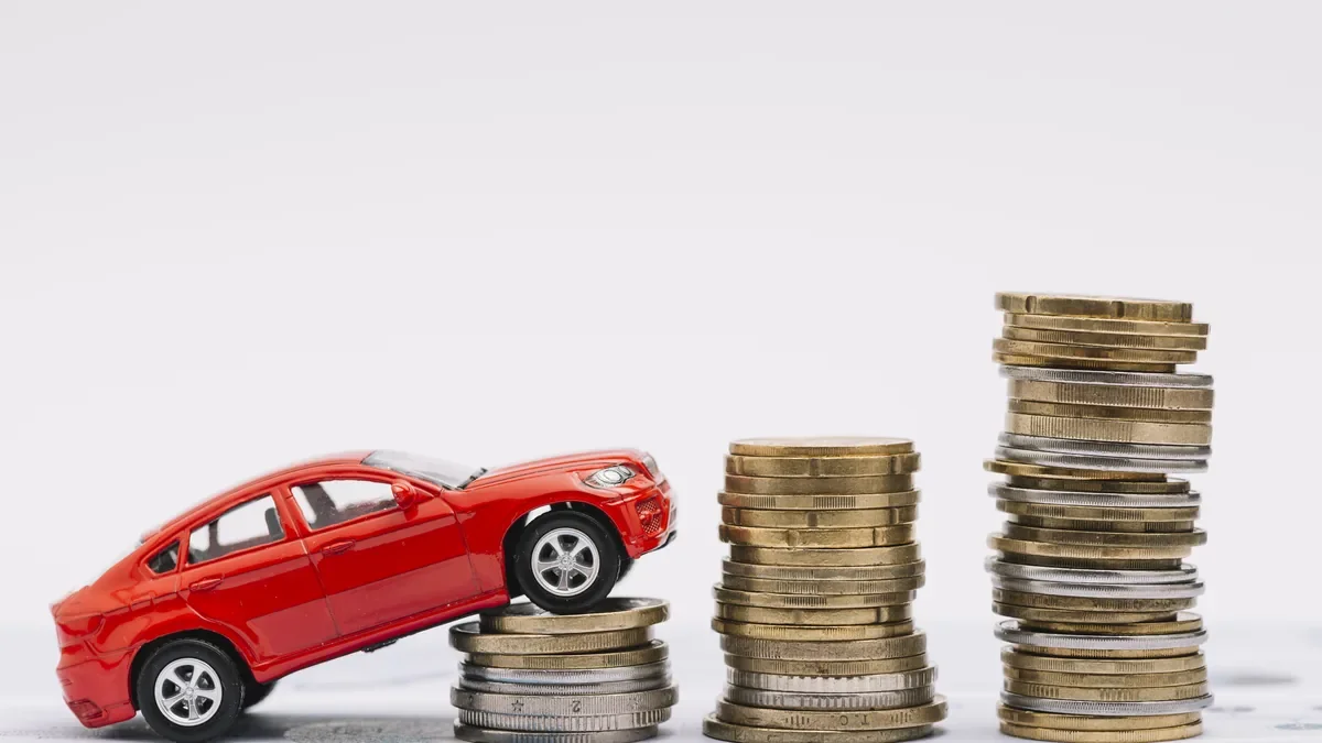 Red toy car climbing a row of coin stacks that grow taller